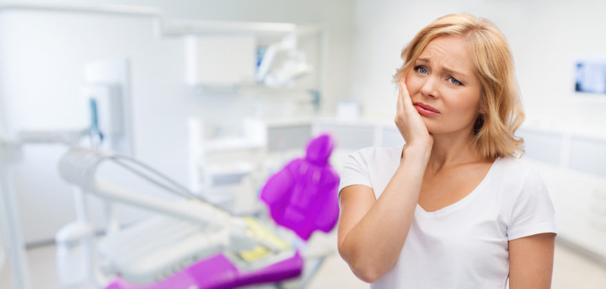 unhappy woman suffering toothache at dental office